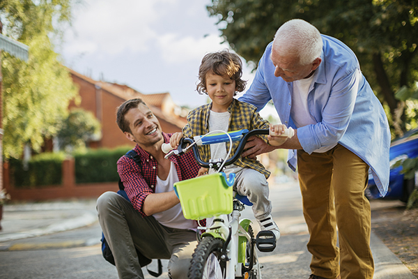 Adults teaching a child to ride a bicycle.